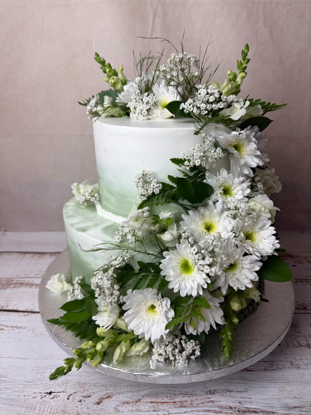 Two-tier anniversary cake covered in white daisies